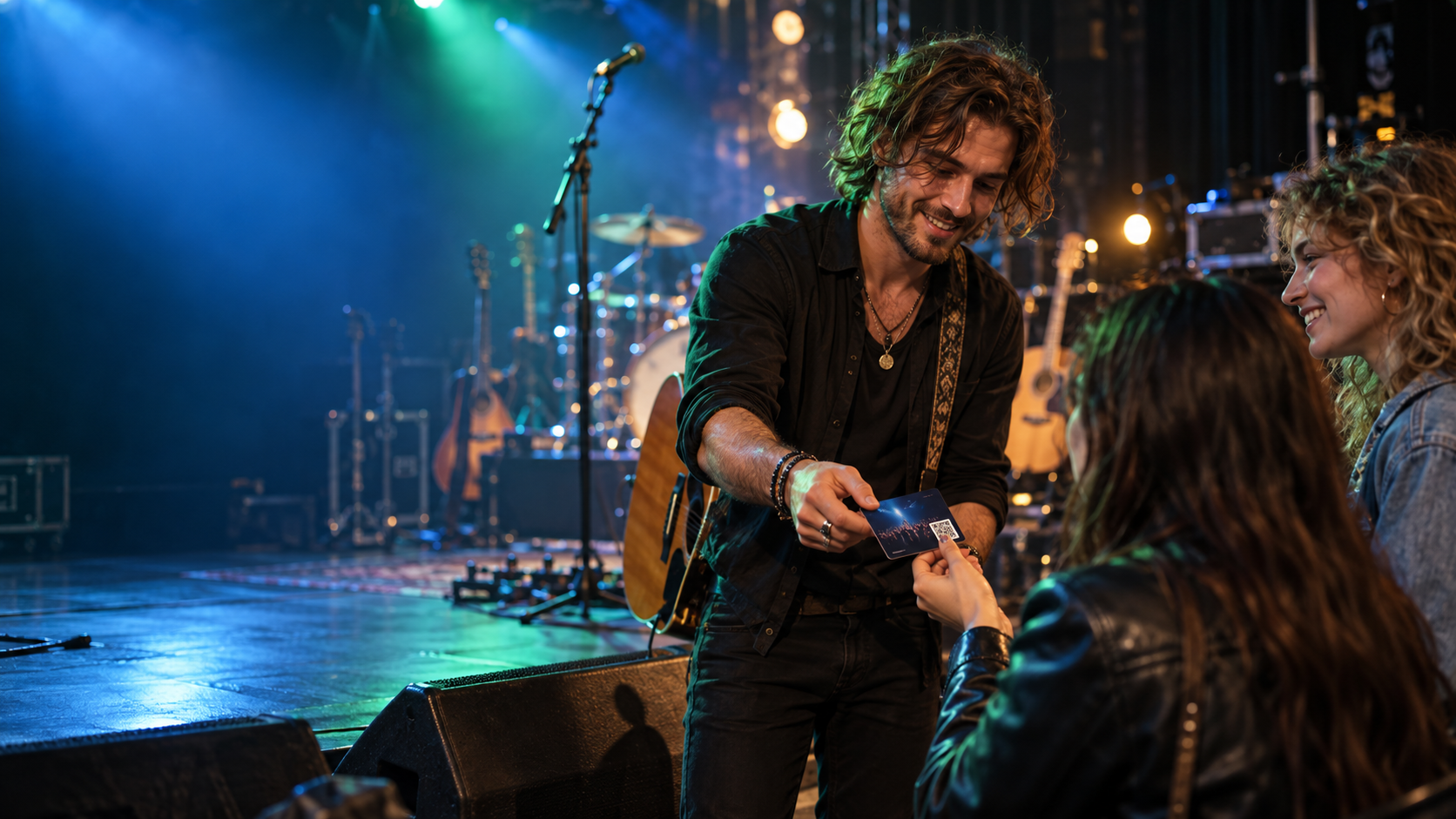 A musician on a lit stage hands a small card to fans in the front row